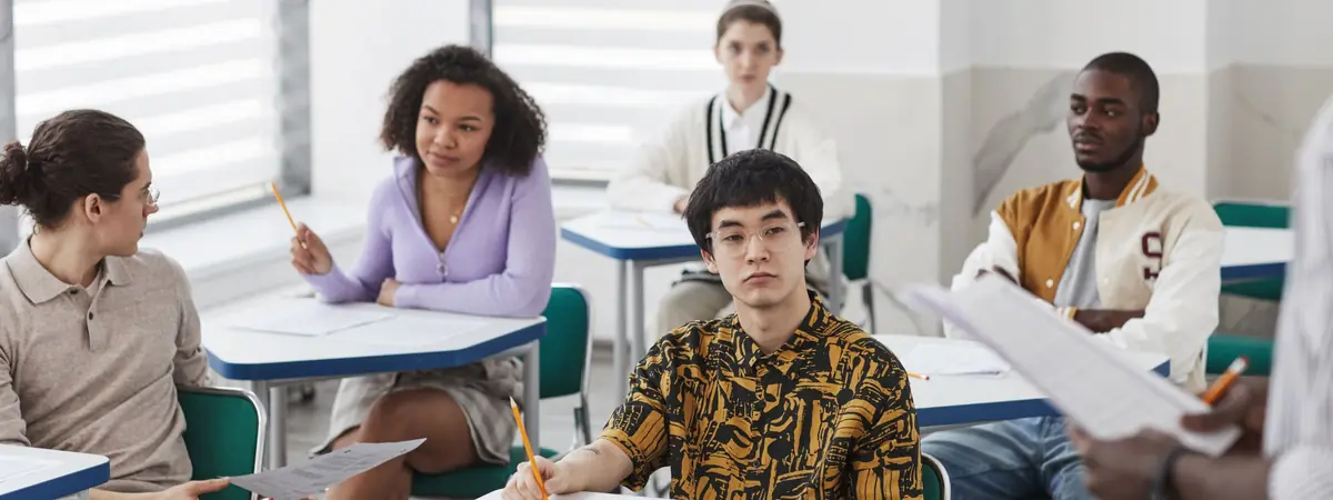 Five students sit at small desks in a classroom, working toward an associate degree in criminal justice.