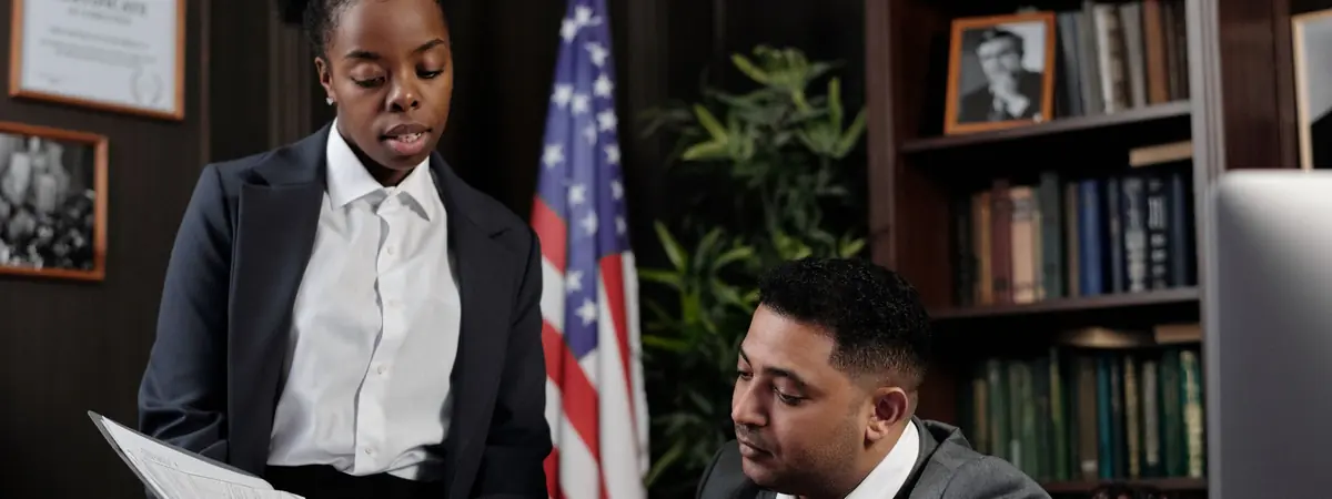 Two professionals review a folder in an office, a setting for jobs with a criminal justice degree.