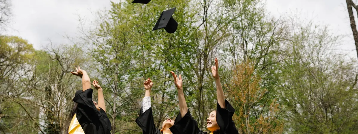 Graduates in black gowns raise their arms as a mortarboard flies up, a milestone for criminal justice majors.