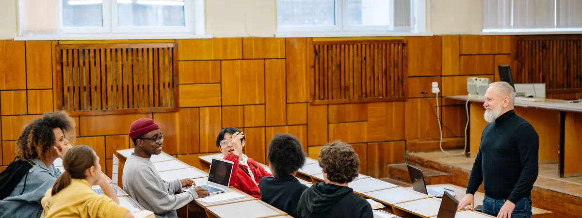 A professor talks with students at laptops in a classroom, for a masters in criminal justice no GRE.