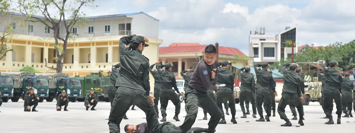 Uniformed officers practice a drill on an open training ground, for a criminal justice degree for police officers.